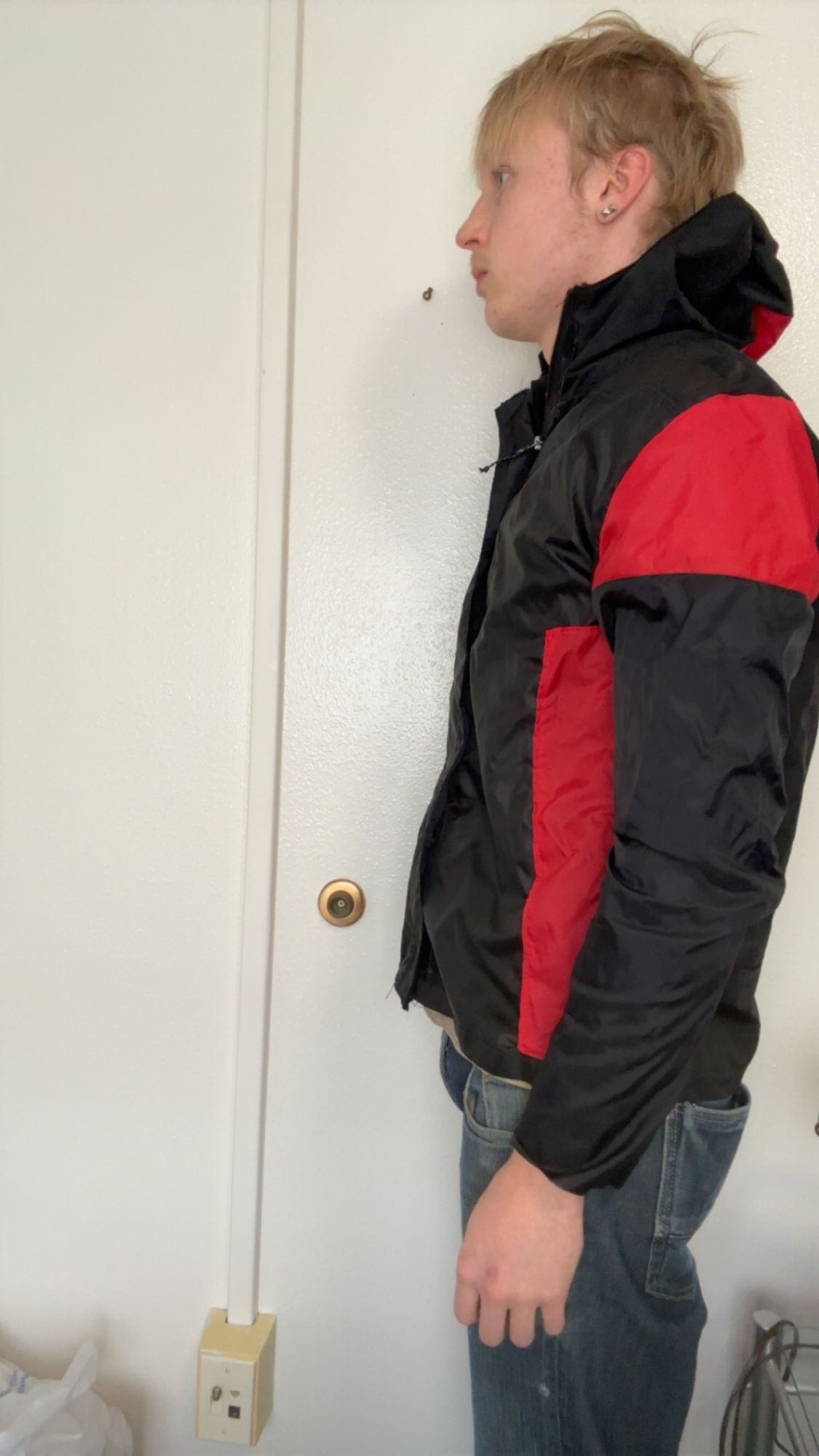 Black and red technical rain jacket, back view, hood up